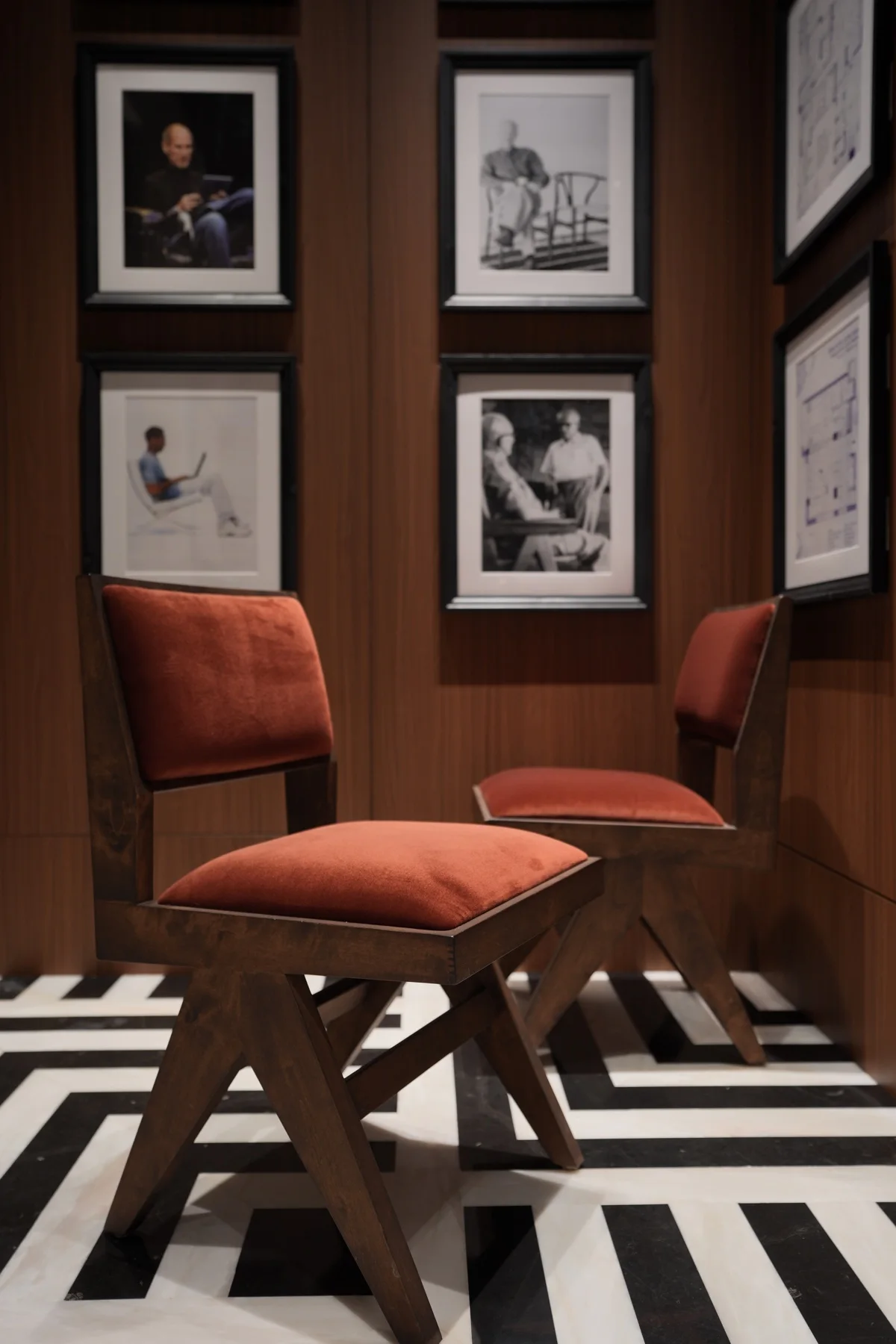 Red upholstered timber chairs in a portrait-lined interior
