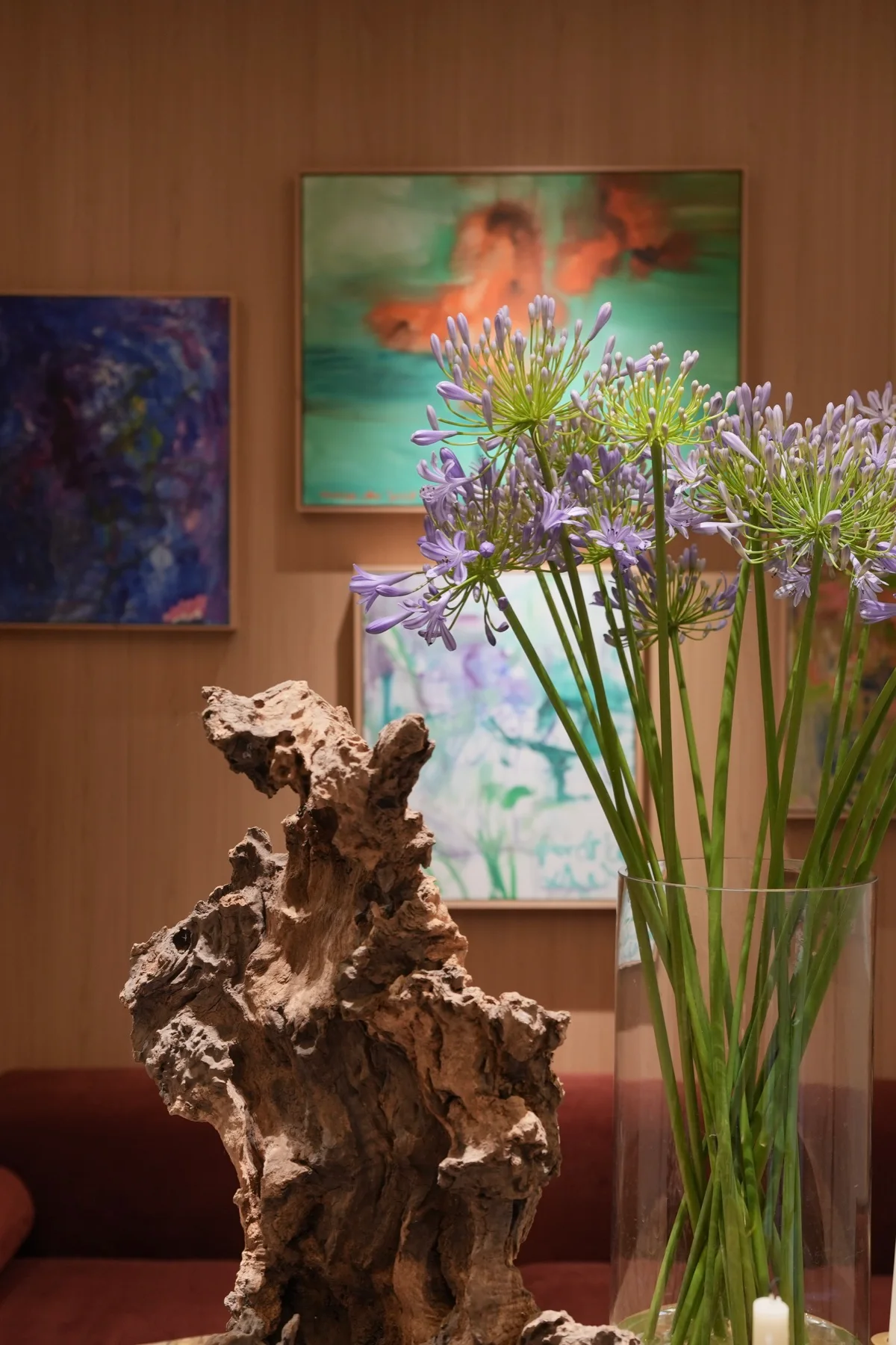 Purple flowers and a sculptural timber object displayed with artwork